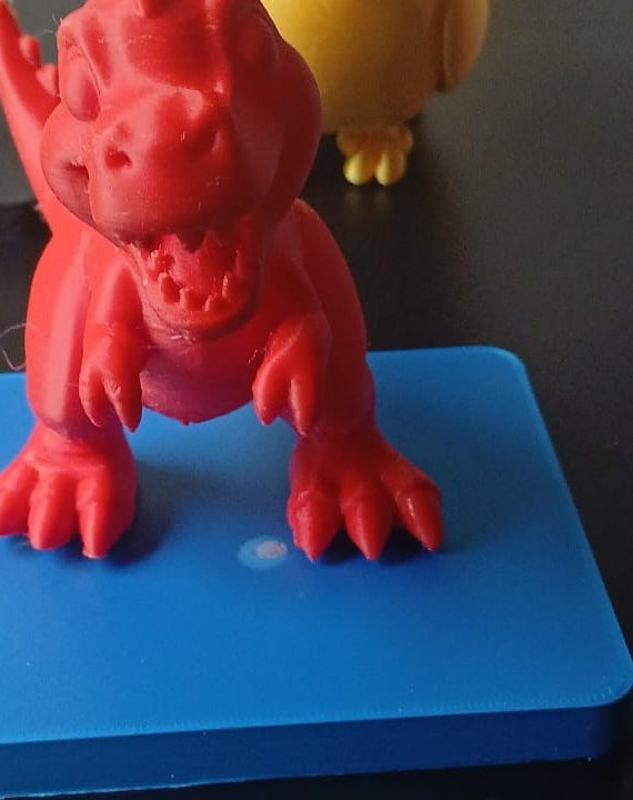 Gedruckter roter Dinosaurier aus PLA auf blauer Platte